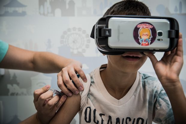 Enzo Fraga, 9, toma vacina enquanto "participa" de animao com culos de realidade virtual
