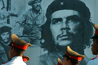 Soldados cubanos passam por cartaz com foto de Che Guevara; turistas e admiradores homenageiam revolucionário argentino