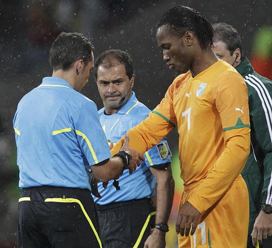 O juiz uruguaio Jorge Larrionda confere a proteção no braço direito de Didier Drogba antes de jogo contra Portugal