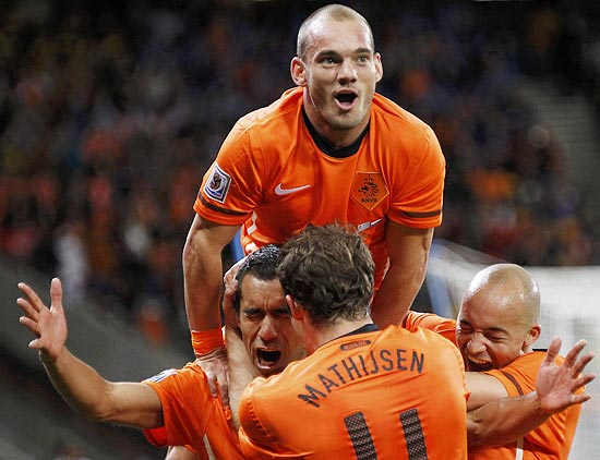 Netherlands' Giovanni van Bronckhorst (L) celebrates his goal with team mates including Joris Mathijsen (4) and Wesley Sneijder (top) during the 2010 World Cup semi-final soccer match against Uruguay at Green Point stadium in Cape Town July 6, 2010. REUTERS/Mike Hutchings (SOUTH AFRICA - Tags: SPORT SOCCER WORLD CUP)