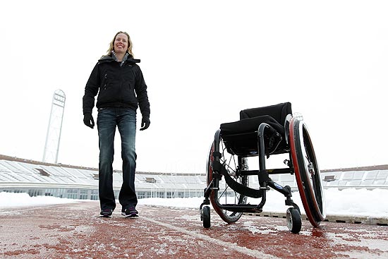 ORG XMIT: AMS104 Monique van der Vorst poses near her wheelchair at the Olympic stadium in Amsterdam, Netherlands, Tuesday, Dec. 21, 2010. Almost half her life, van der Vorst was wheelchair bound until a freak accident in spring training 2010 sent uncontrollable, spastic shudders through her legs. It was as if a jumper cable set her old body in motion again, the body she had before she became paralyzed barely a teenager. Now at 26, she is starting a third life, literally learning how to walk and, hopefully, run again, dealing with fortitude she no longer held possible. (AP Photo/Bas Czerwinski)