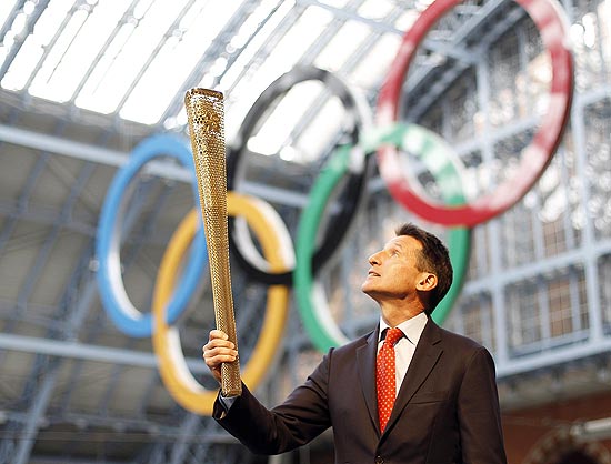 O presidente do comitê organizador Sebastian Coe segura a tocha olímpica em uma estação de Londres