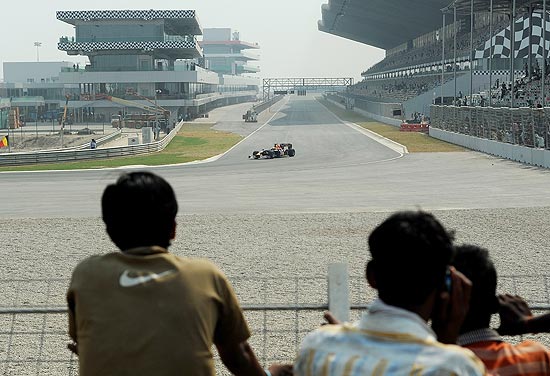 Operrios observam carro da Red Bull no circuito indiano; clique na foto e veja galeria