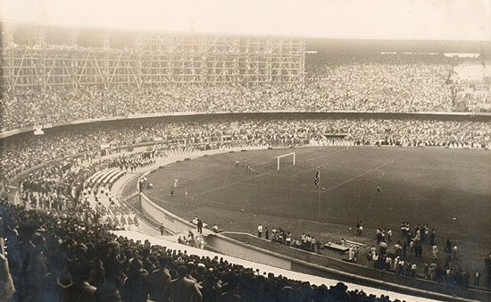 Imagem mostra arquibancada cheia de torcedores no jogo de inauguração do estádio