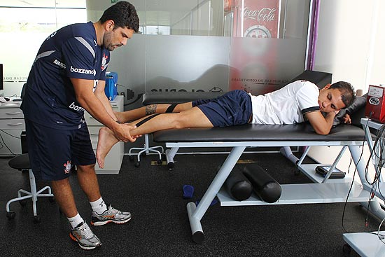 O fisioterapeuta do Corinthians, Bruno Mazziotti, aplica a bandagem no lateral Fábio Santos; veja galeria