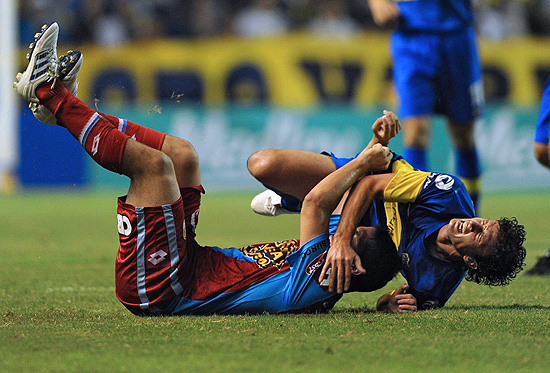 Pablo Ledesma (dir.), do Boca, e Ivan Marcone caem durante a partida na Bombonera