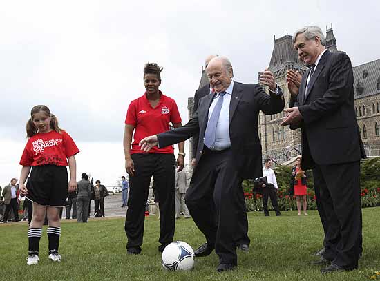  Blatter chuta uma bola entre a goleira canadense Karina Leblanc e o presidente da federação local, Dominique Maestracci, em Ottawa