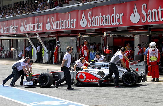 Mecânicos da McLaren empurram carro de Lewis Hamilton ao final do treino classificatório