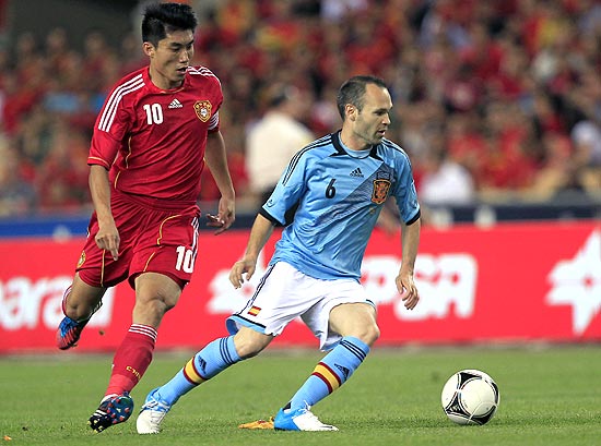 Andrés Iniesta domina a bola marcado por Zheng Zhi, da China, em amistoso em Sevilha