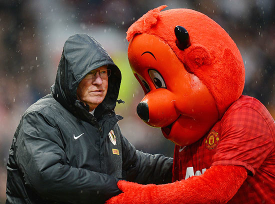 O técnico Alex Ferguson cumprimenta a mascote do Manchester United, o 'Fred the Red'