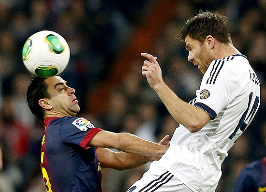Xabi Alonso, do Real Madri, disputa jogada contra Xavi Hernández, do Barça, ambos jogam juntos pela Espanha