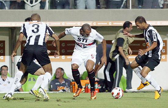 Cercado por jogadores do Atlético-MG, Luis Fabiano tenta uma jogada para o São Paulo