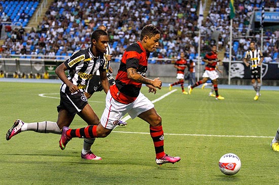 O estreante Carlos Eduardo, do Flamengo, corre com a bola acompanhado por Jlio Csar, do Botafogo
