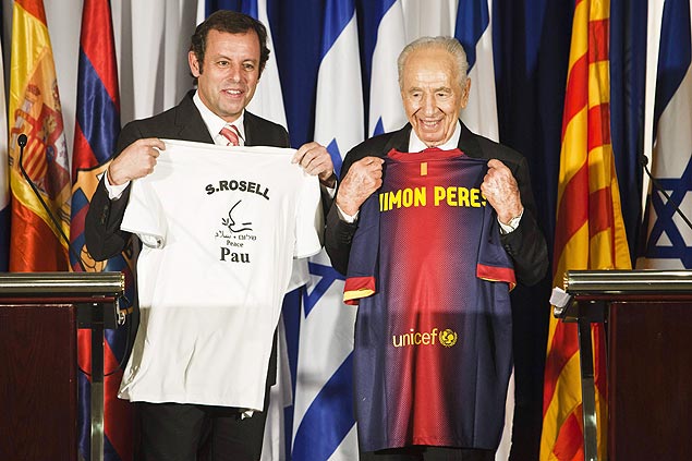O presidente de Israel, Shimon Peres, e o mandatrio do Barcelona, Sandro Rosell, mostram camisas que ganharam durante encontro