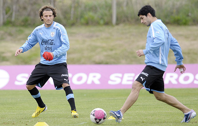 Diego Forlan olha Luis Suarez chutar a bola durante treino no Uruguai