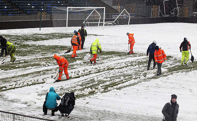 Trabalhadores tiram neve do campo onde a Irlanda do Norte enfrentaria a Rssia nesta sexta-feira