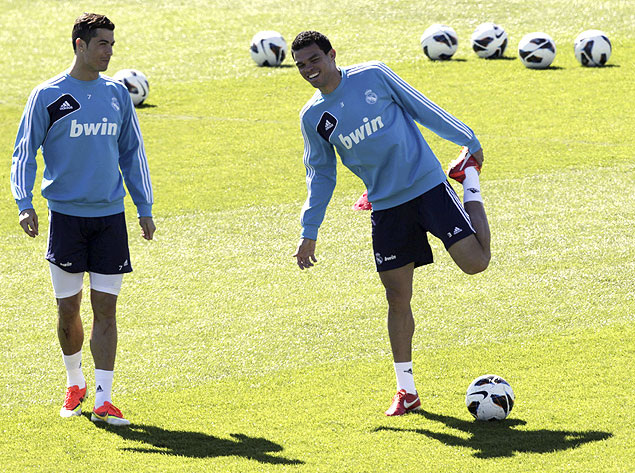 Observado por Cristiano Ronaldo (esq.), Pepe se alonga durante treinamento do Real Madrid 
