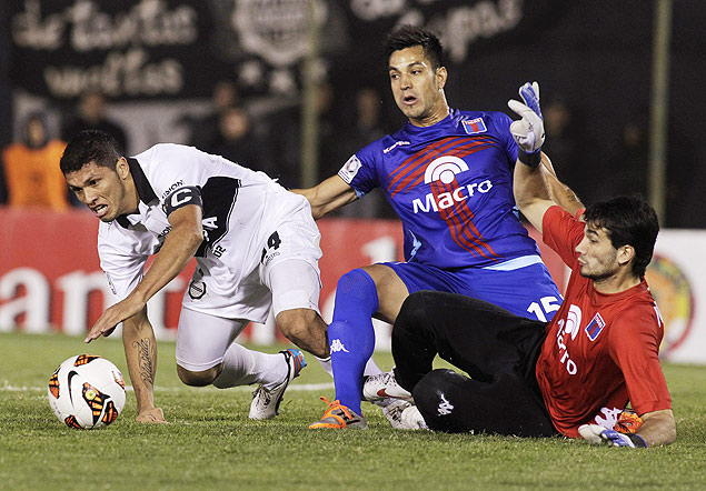 Gaston Angel Daz (centro) e o goleiro Javier Hernan Garcia, ambos do Tigre, brigam pela bola com Eduardo Aranda do Olimpia, durante o jogo