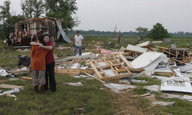 Mulheres se abraam em Shawnee, no estado americano de Oklahoma, aps uma srie de tornados atingir a regio, danificando casas e arrancando rvores 