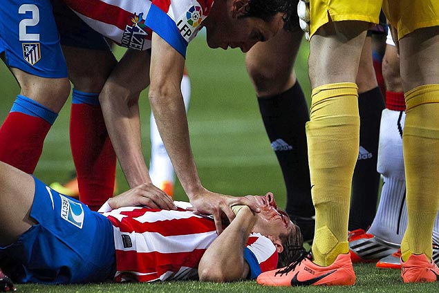 O lateral esquerdo Filipe Luís é atendido no gramado após sofrer uma pancada do escocês Alan Hutton, em partida pelo Campeonato Espanhol