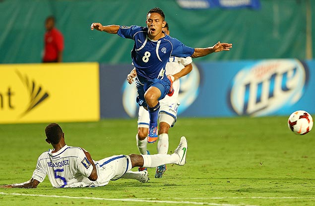 Osael Romero, de El Salvador, tenta saltar para escapar de uma rasteira durante jogo contra Honduras; jogador  um dos suspensos pela federao