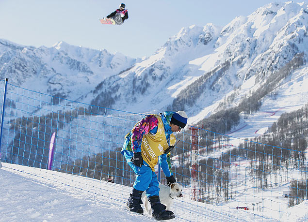 Funcionrio conduz co para longe de pista de snowboard durante treino em Sochi