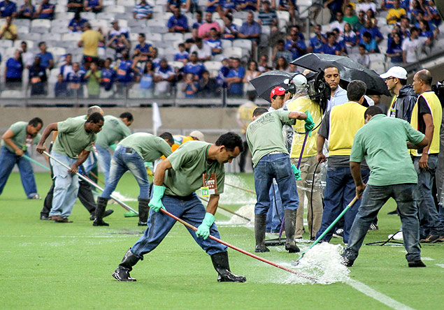 Funcionários da Minas Arena retiram água de dentro do campo antes da partida entre Cruzeiro e Minas Boca, pelo Campeonato Mineiro