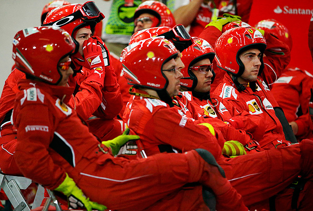 Mecnicos da Ferrari acompanham uma corrida nos boxes da equipe italiana