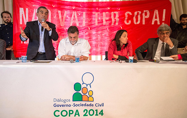 Ministro Gilberto Carvalho fala enquanto manifestantes estendem faixa de protesto contra a Copa no Brasil