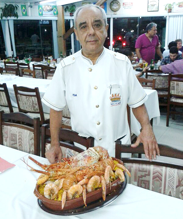 O garom Mario Lima mostra a paella valenciana