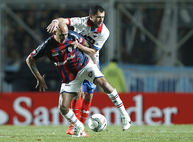 Mercier, do San Lorenzo, protege a bola, marcado por Bareiro, do Nacional, do Paraguai, na final da Libertadores