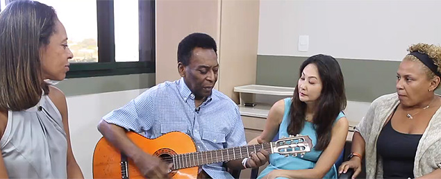 Imagem do vídeo em que Pelé aparece tocando violão ao lado de filhas e da namorada