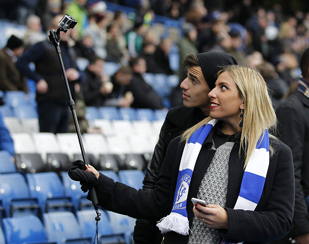 Dois torcedores usam "pau de selfie" em partida de futebol entre os time Chelsea e West Ham United, em Londres