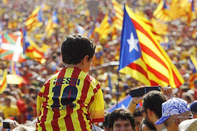 A boy wearing Lionel Messi's jersey sits on the shoulders of a relative as Catalans holding independentist flags (Estelada) gather on Gran Via de les Corts Catalanes during celebrations of Catalonia National Day (Diada) in Barcelona on September 11, 2014. Red and yellow flags filled the streets of Barcelona today as Catalan nationalists fired up by Scotland's independence referendum rallied to demand a vote on breaking away from Spain. Demonstrators planned to mass in the late afternoon along two central Barcelona avenues in the shape of a giant letter "V" for vote. AFP PHOTO/ QUIQUE GARCIA ORG XMIT: SEB1168