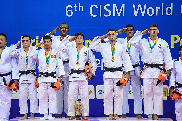 Equipo masculino de judo realiza un saludo militar tras recibir una medalla de oro.
