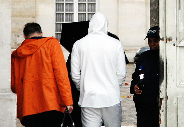 Benzema, com casaco branco, chega para depoimento  polcia