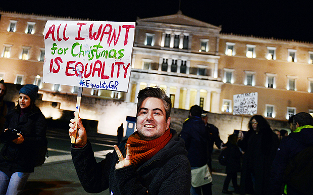 A man holds a placard reading "All I want for Christmas is equality" during a demonstration of gay rights activists and members of the Athens LGBT community outside the Greek parliament in Athens on December 22, 2015 as parliament votes on granting same-sex couples the right to a civil union, despite strong opposition from the influential Orthodox church. Greek government is seeking to meet its obligations after it was condemned for anti-gay discrimination by the European Court of Human Rights in 2013. / AFP / LOUISA GOULIAMAKI ORG XMIT: LOU4335
