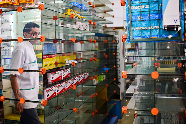 Funcionrio passa por prateleiras praticamente vazias em uma farmcia de Caracas