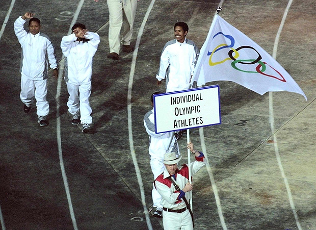 ORG XMIT: 152301_1.tif Jogos Olímpicos de Sydney (Austrália), 2000: quatro atletas de Timor Leste desfilam com uniformes brancos e sob a bandeira do COI (Comitê Olímpico Internacional) na cerimônia de abertura dos Jogos Olímpicos de Sydney (Austrália). Cerca de 10.300 atletas de 199 países começam a disputa dos 27º Jogos da era moderna. Serão 230 provas em 40 modalidades esportivas. Os Jogos Olímpicos de Sydney-2000 vão até o dia 1º de outubro (cerimônia de encerramento). *** Athletes from East Timor, invited as Individual Olympic Athletes by the International Olympic Committee (IOC) march during the "Parade of Nations" at the opening ceremony of the Sydney 2000 Summer Olympic Games 15 September 2000. AFP PHOTO / Joel SAGET 
