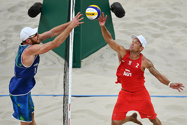 Brazil's Alison Cerutti (L) tries to block the ball in front of Austria's Alexander Horst during the men's beach volleyball qualifying match between Brazil and Austria at the Beach Volley Arena in Rio de Janeiro on August 8, 2016, for the Rio 2016 Olympic Games. / AFP PHOTO / Leon NEAL