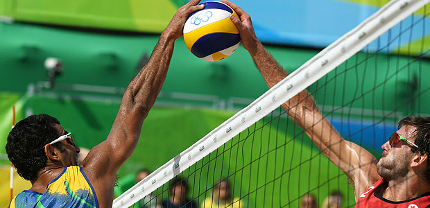 Brazil's Pedro Solberg (L) jumps to block the ball during the men's beach volleyball qualifying match between Brazil and Canada at the Beach Volley Arena in Rio de Janeiro on August 9, 2016, for the Rio 2016 Olympic Games. / AFP PHOTO / Yasuyoshi Chiba