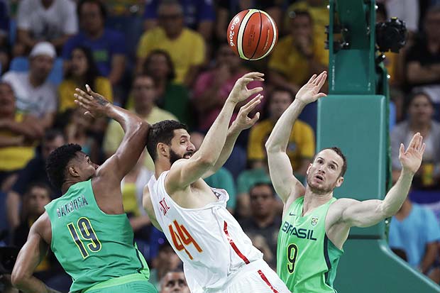 Spain's Nikola Mirotic, center, passes between Brazil's Leandro Barbosa, left, and Marcelinho Huertas, right, during a basketball game at the 2016 Summer Olympics in Rio de Janeiro, Brazil, Tuesday, Aug. 9, 2016. (AP Photo/Charlie Neibergall) ORG XMIT: OBKO101