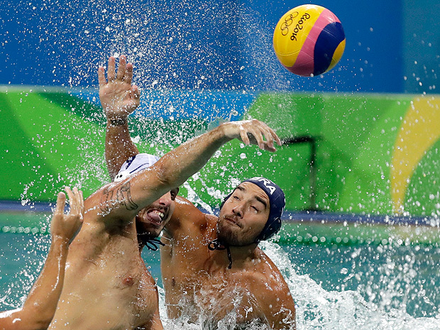 O grego Konstantinos Mourikis, à esquerda, passa a bola enquanto o brasileiro Ruda Franco tenta o bloqueio