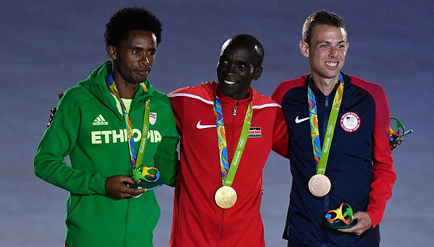 (From L) Silver medallist Ethiopia's Feyisa Liesa, gold medallist Kenya's Eliud Kipchoge and bronze medallist USA's Galen Rupp pose on the podium of the men's marathon during the closing ceremony of the Rio 2016 Olympic Games at the Maracana stadium in Rio de Janeiro on August 21, 2016. / AFP PHOTO / Fabrice COFFRINI