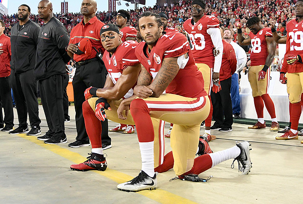 Colin Kaepernick, no centro da imagem, e o colega Eric Reid, do San Francisco 49ers, protestam durante a execução do hino dos EUA antes de partida em Los Angeles