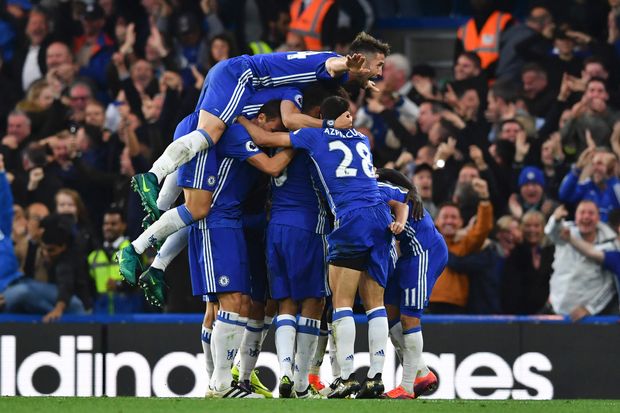 Chelsea's English defender Gary Cahill (top) jumps onto the huddle to join the celebrates after Chelsea's French midfielder N'Golo Kante scored their fourth goal during the English Premier League football match between Chelsea and Manchester United at Stamford Bridge in London on October 23, 2016