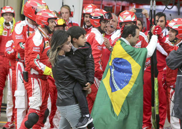 Com a bandeira do Brasil nas costas, Felipe Massa  cumprimentado por membros da equipe da Ferrari aps ser forado a abandonar GP Brasil
