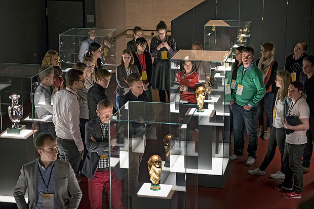 Visitors look at trophies from some of Germany's most important historical soccer victories, at the German Football Museum in Dortmund, Germany, March 28, 2107. Fussball, as soccer is known in Germany, looms large in the national psyche: There are 25,075 local soccer clubs and Freekickerz, a soccer website, is the biggest YouTube site in Germany, with more than five million subscribers. (Gordon Welters/The New York Times)