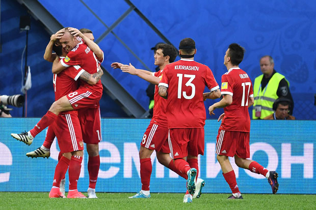 Russia's midfielder Denis Glushakov (2nd L), who scored the first goal, jumps and hugs Russia's forward Fedor Smolov, who scored the team's second goal, after Russian beat New Zealand 2-0 in the 2017 Confederations Cup group A football match between Russia and New Zealand at the Krestovsky Stadium in Saint-Petersburg on June 17, 2017. / AFP PHOTO / Kirill KUDRYAVTSEV