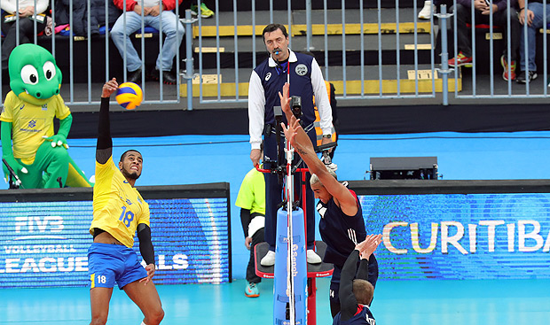 Referee Andrey Zenovich pays attention as Brazilian Ricardo Lucarelli spikes and American players try to block him